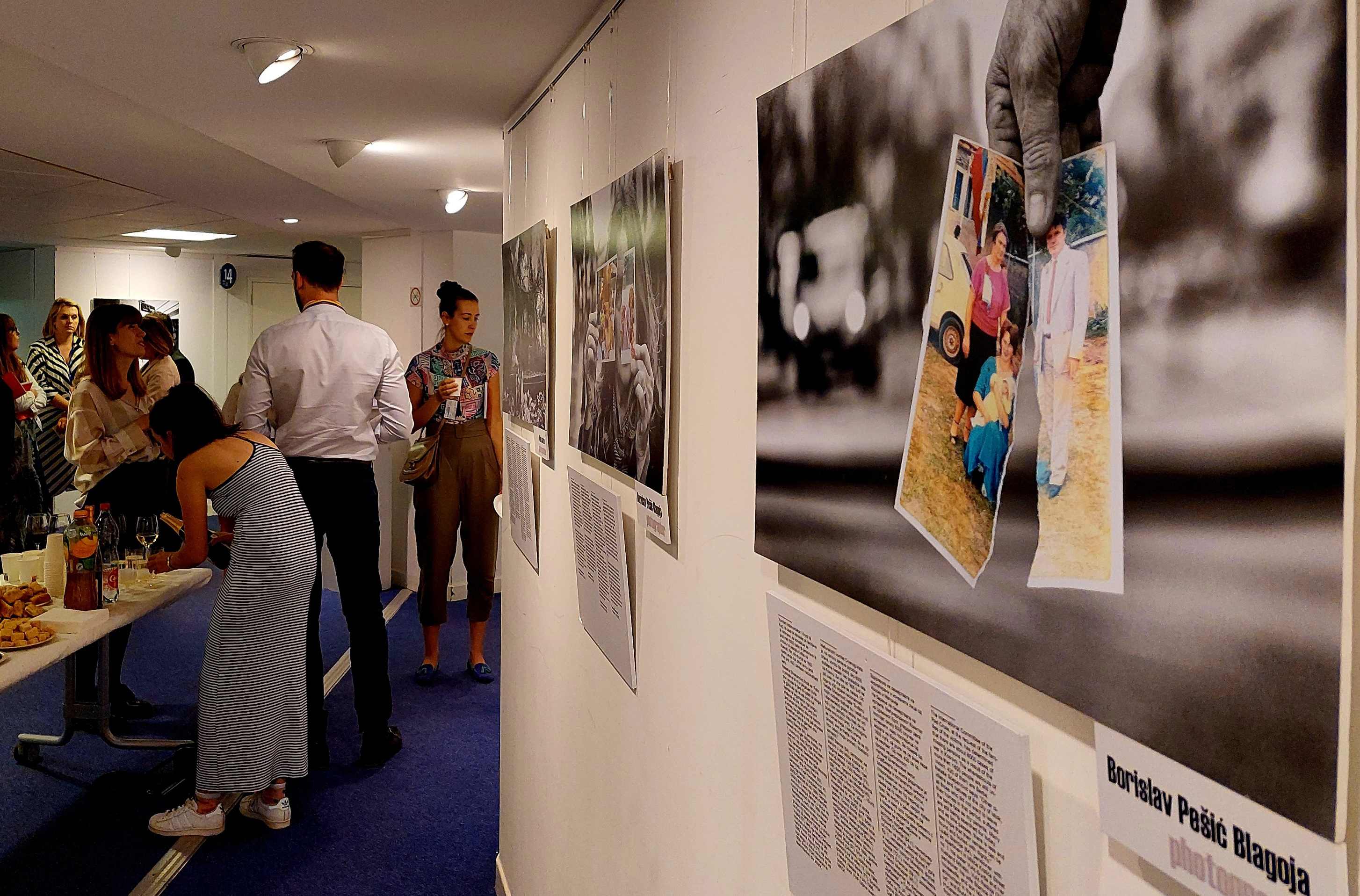 Audience members look at photographs displayed on the wall.