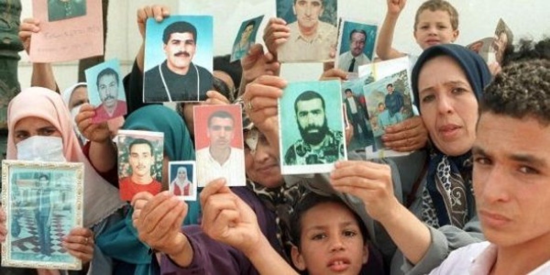 Image of a group of women and youth holding up photographs of missing loved ones. 