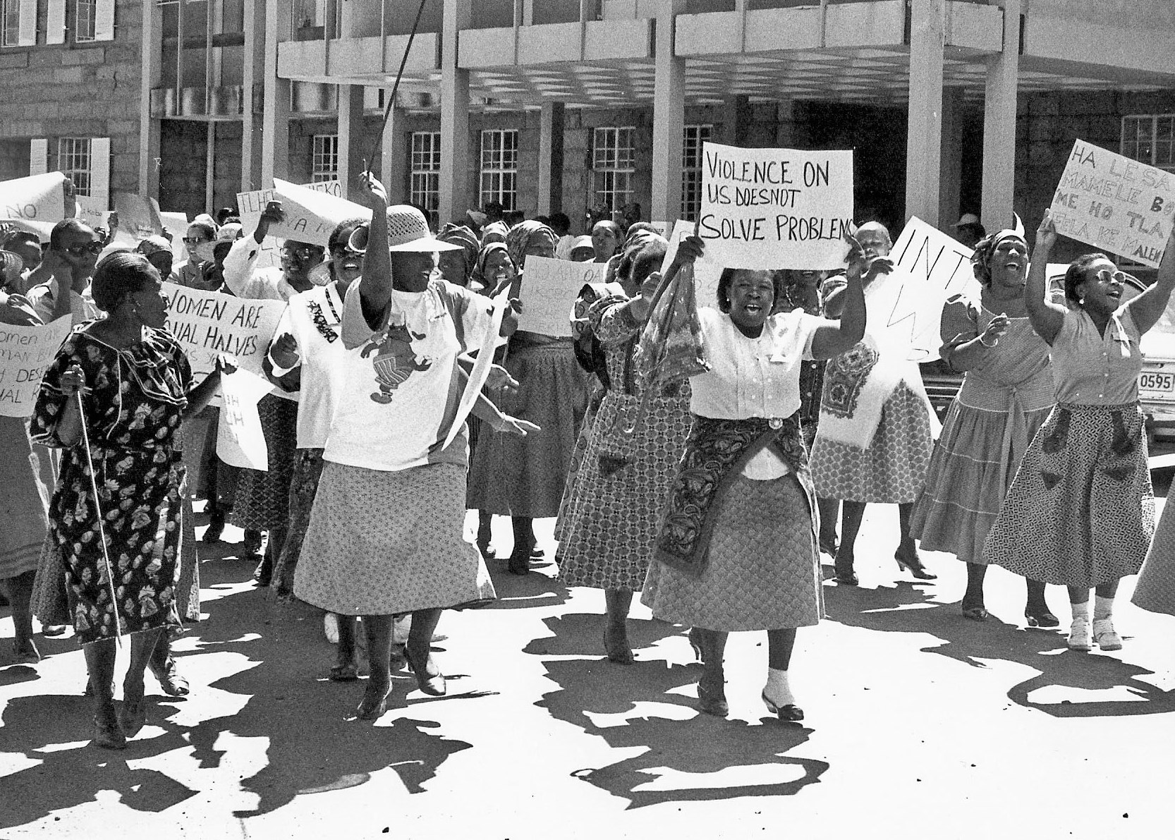Black and white photo of Black women marching in the street holding protest signs.